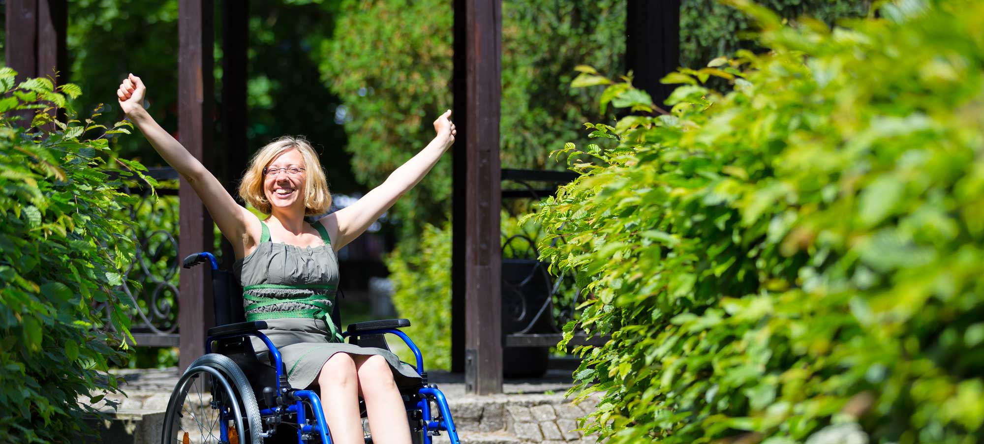 A woman in a wheelchair holding her arms up in joy