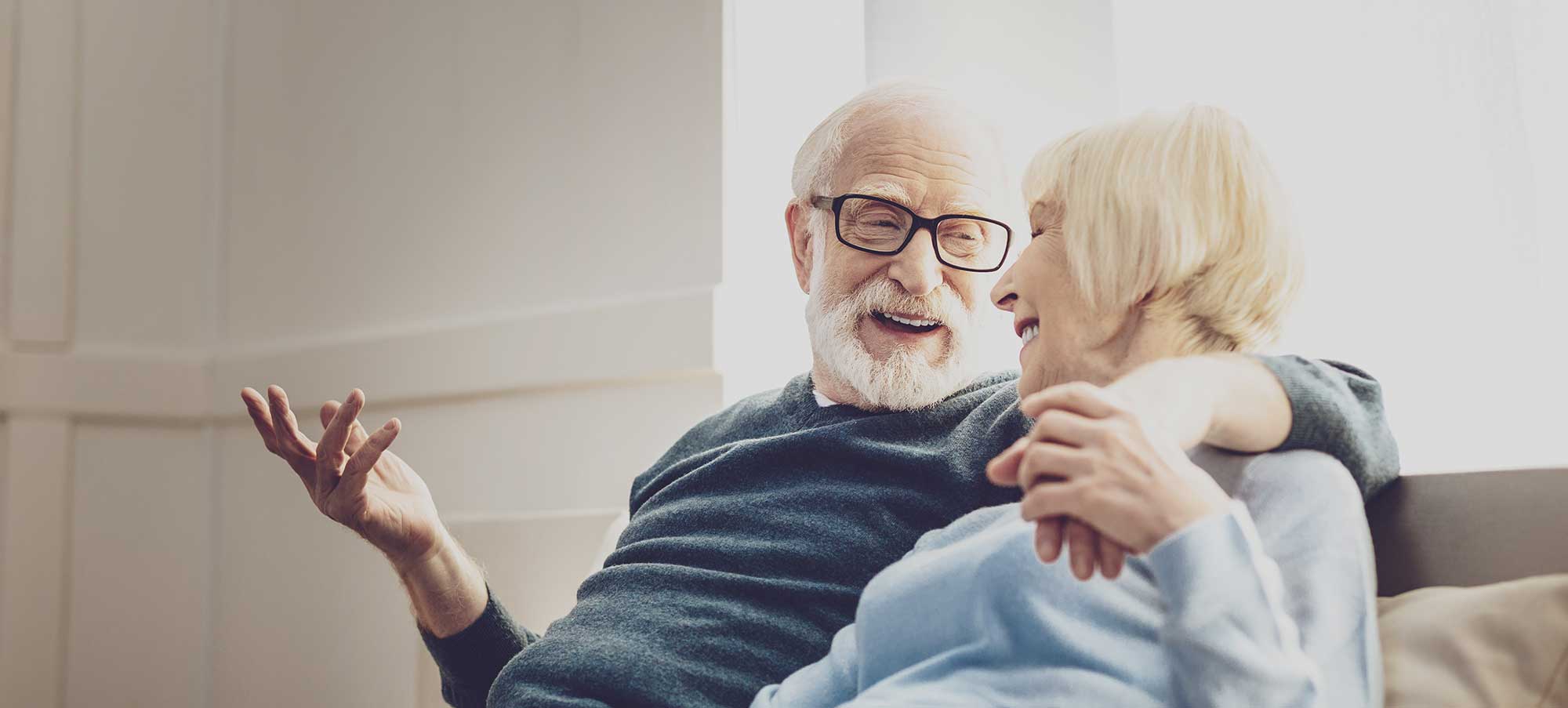 An elderly couple sitting on a couch and laughing