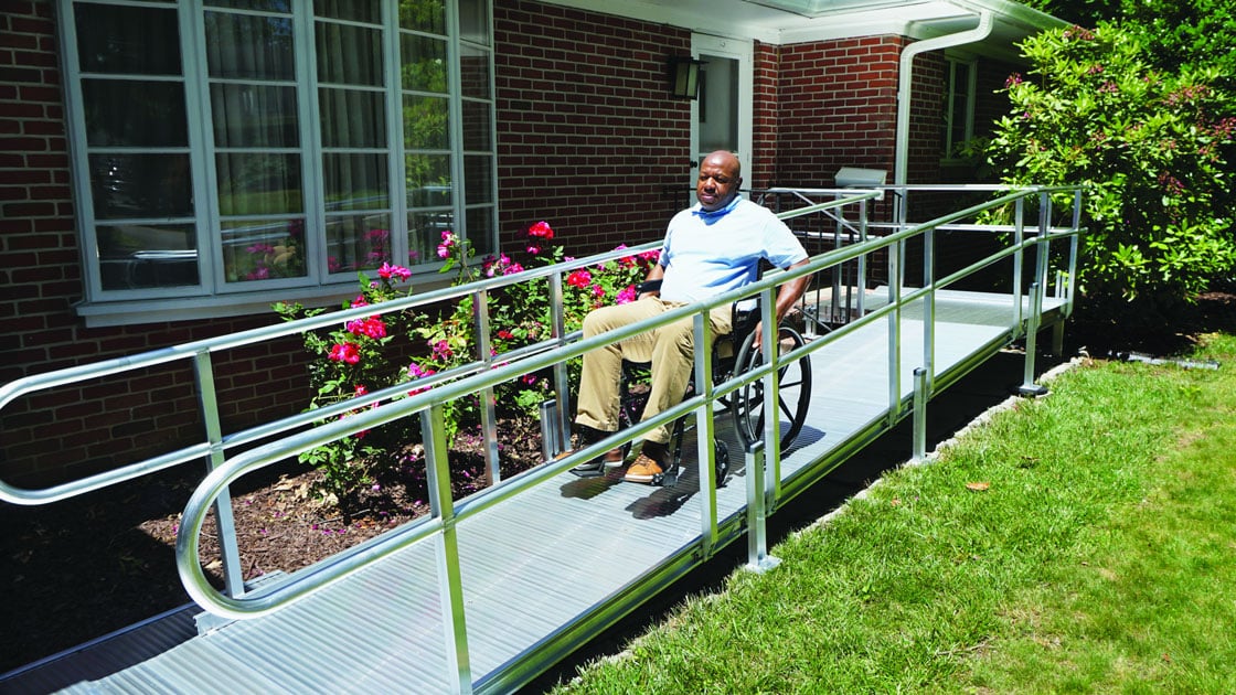An elderly gentleman in a wheelchair using an aluminum ramp