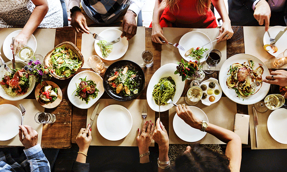 Aerial view of a dinner table full of food and people eating - Prepare Your Home for Handicap Guests