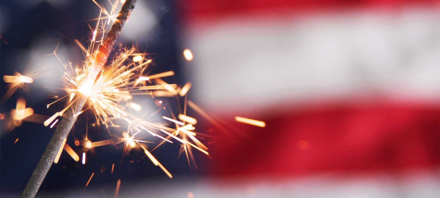 Close up of a sparkler in front of an American flag