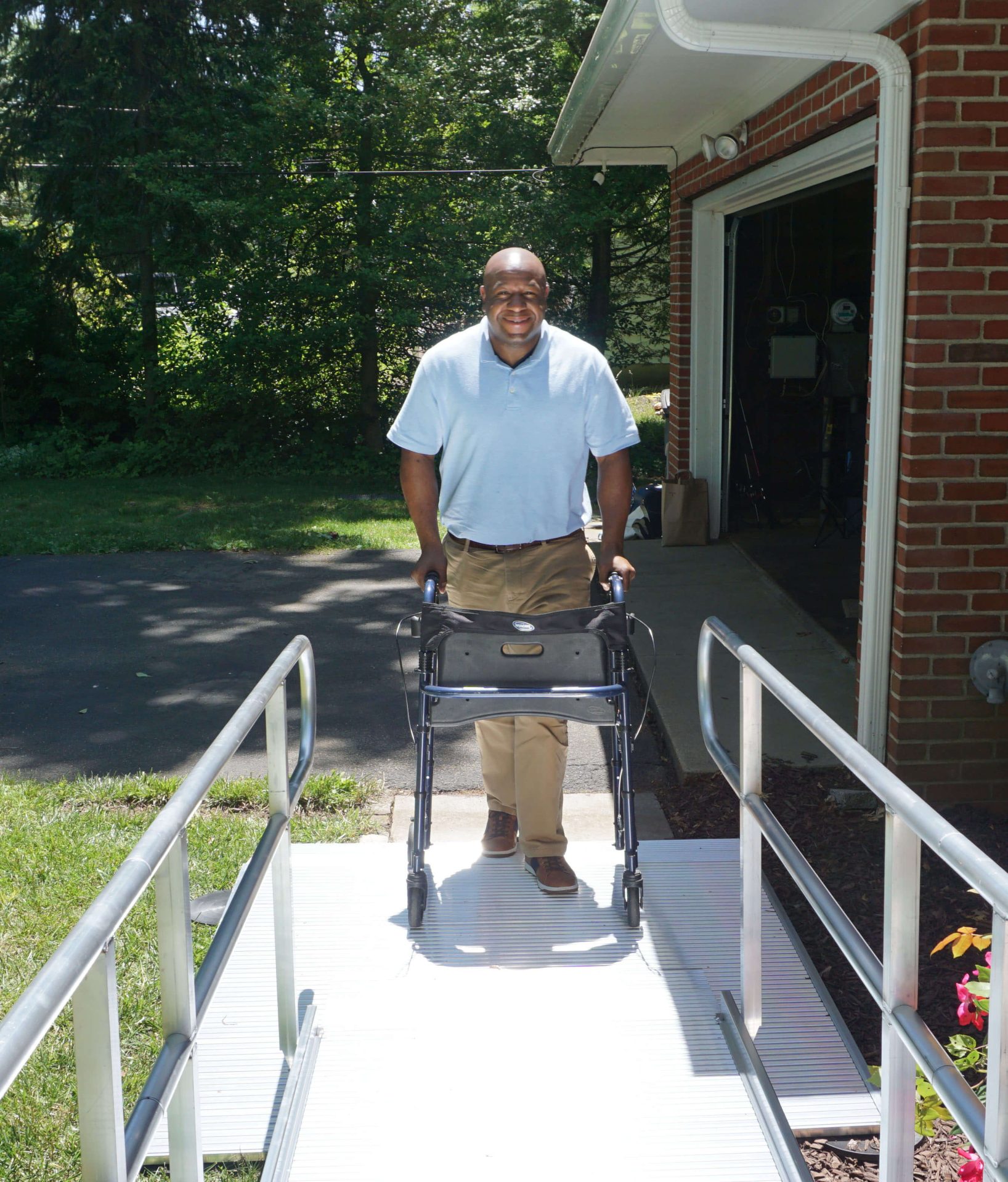 A man walking up a handicap ramp with the aid of a walker