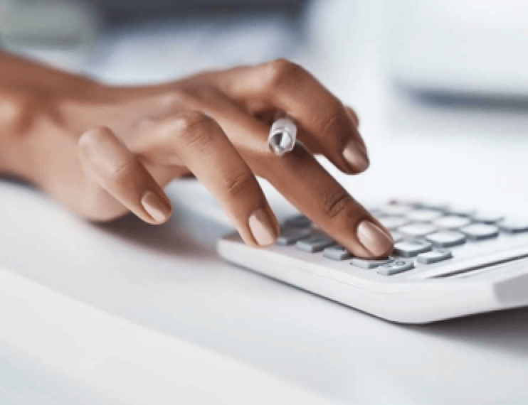 A woman's hand holding a pen and using a calculator