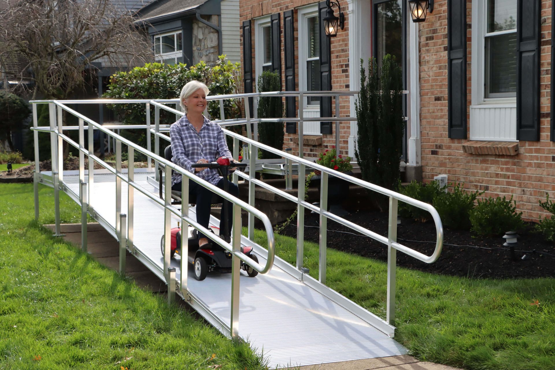 elderly woman on scooter coming down home access ramp